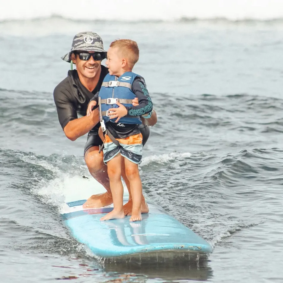 A child catches their first wave during surf lesson at the Guardrails in Maui.