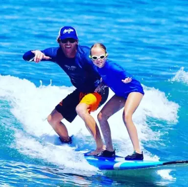 Young surfer riding a wave with an instructor in Maui
